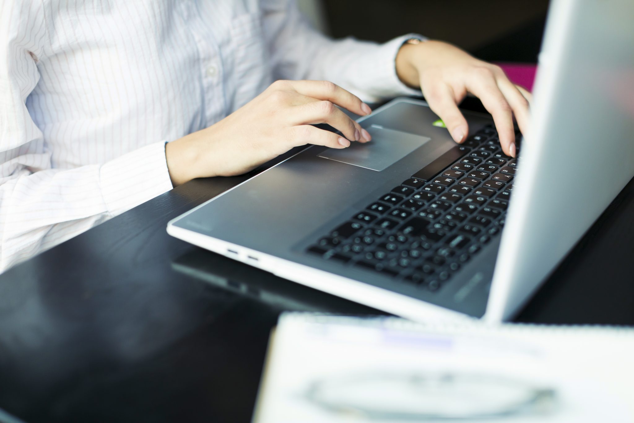 A close-up of a person's hands typing on a laptop keyboard