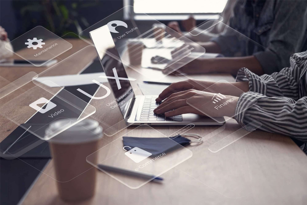 What are Managed Website Services Hands type on a laptop in an office setting, overlaid with glowing holographic icons representing UX User Experience Design