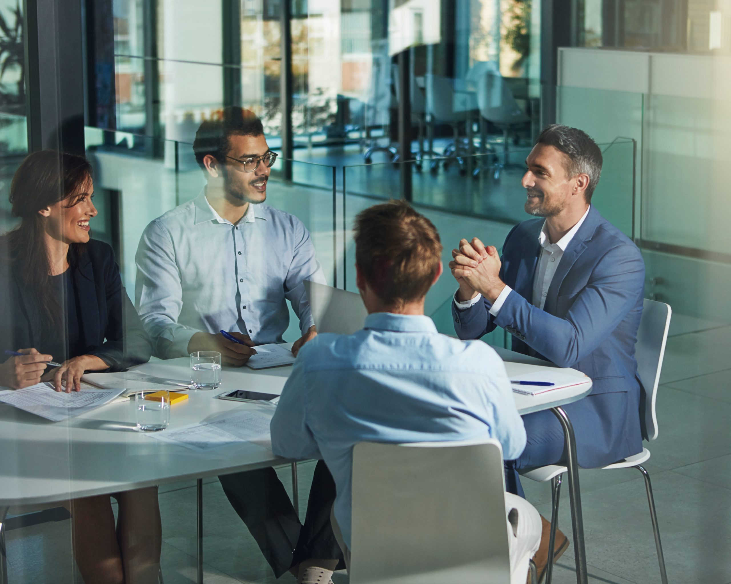 Why Do Businesses Need Managed Website Services Four professionals in a modern office meeting room and collaborating around a conference table.